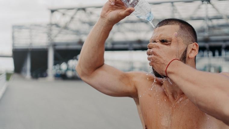 A man pouring water on his head from a water bottle