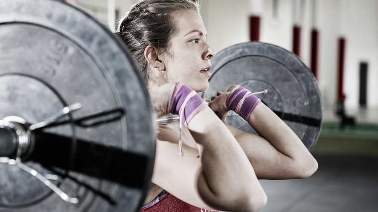 woman wearing wristbands holding barbell with arms bent
