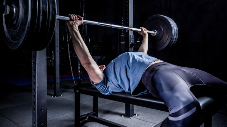 Man lying on flat bench holding barbell overhead