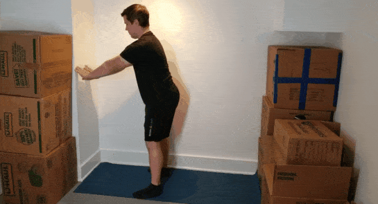 A gif of Coach Jim doing an assisted squat in a small space.