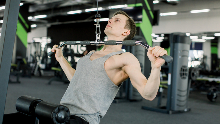 Man in gym performing back exercise with cable machine