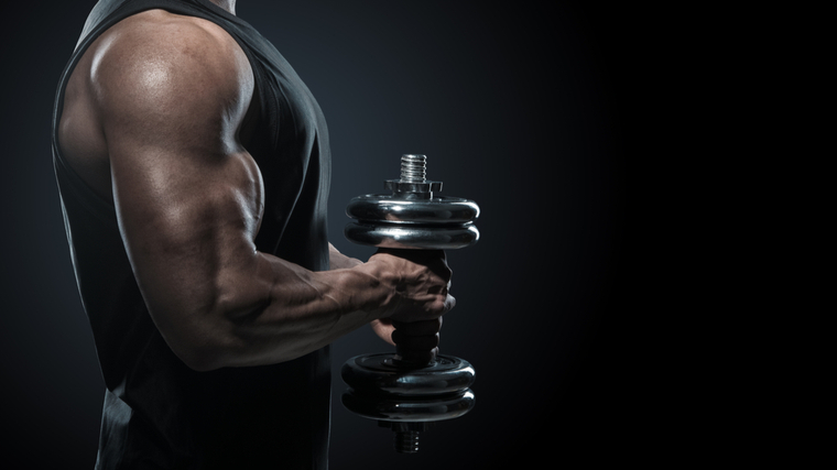 Muscular arm in shadows holding dumbbell