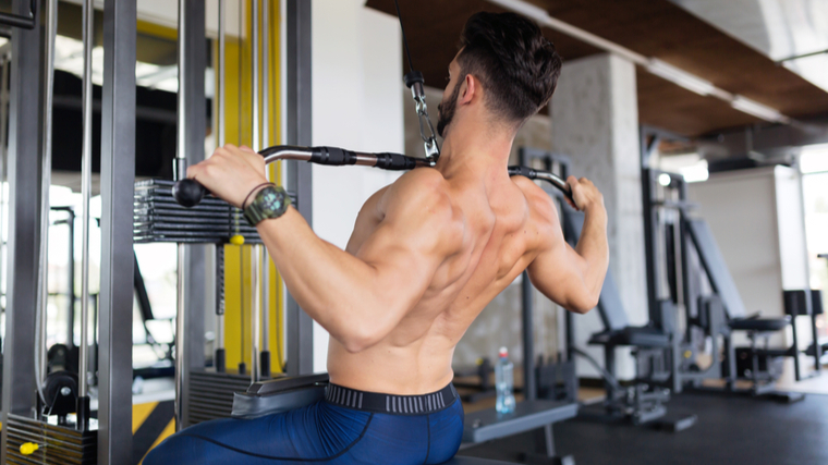 Muscular man in gym performing wide grip pulldown