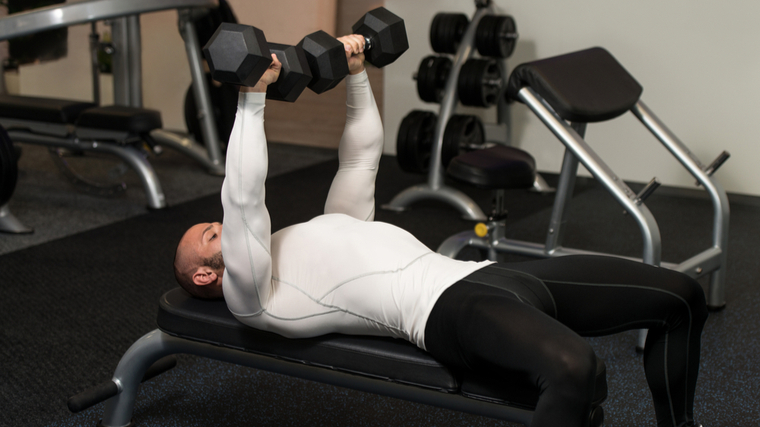 man in gym pressing dumbbells during chest exercise