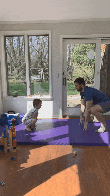 This gif shows both Matt and his kid going from a squat to standing tall, arms up.