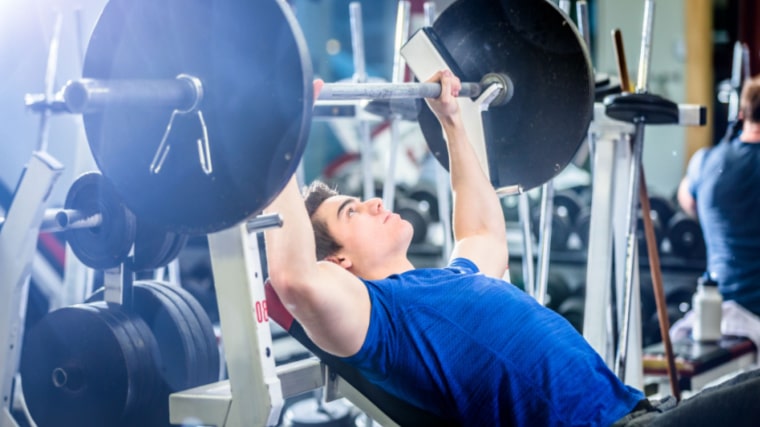 person in gym preparing to press barbell
