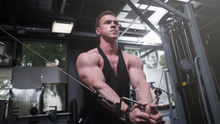 muscular person in gym cable machine