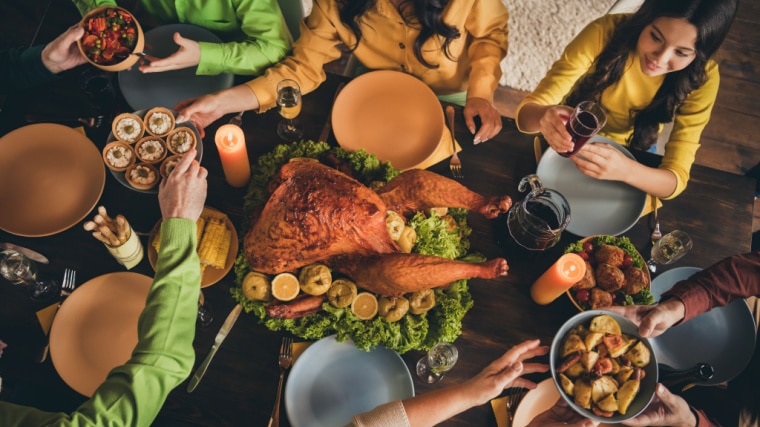 people around dinner table with turkey