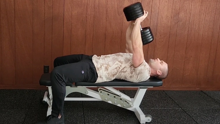Step 2 - A person securely grasping a dumbbell with both hands on the gym bench for a pullover.