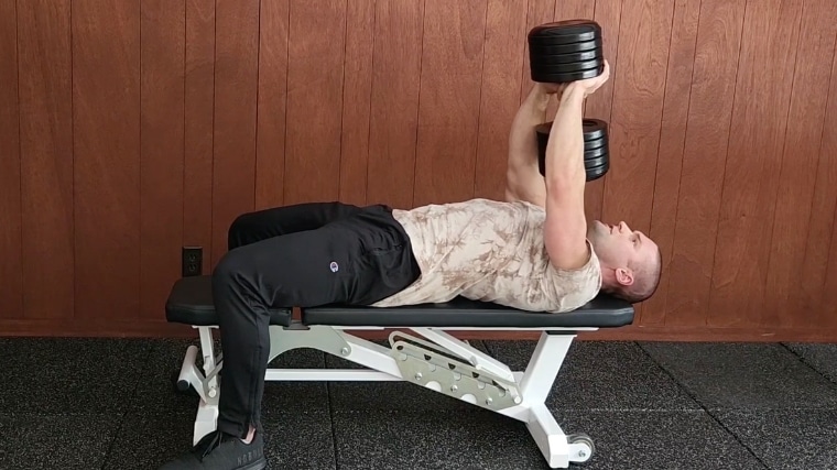 Step 4 - A person securely holding a dumbbell in the top position of a pullover.