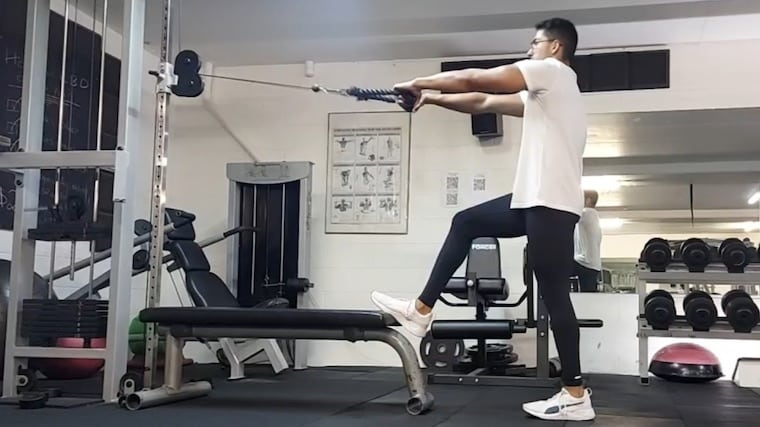 Person in gym doing cable shoulder exercise