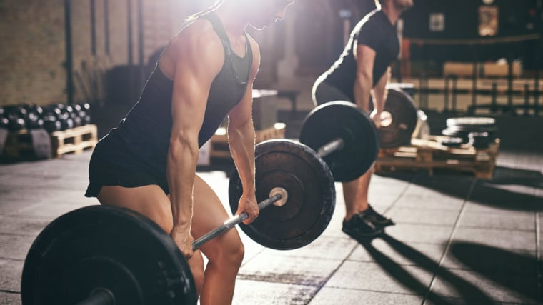 two people in gym lifting barbells from ground