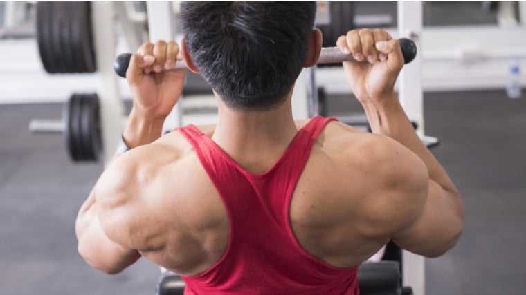 Muscular person in gym flexing back muscle during pulldown exercise