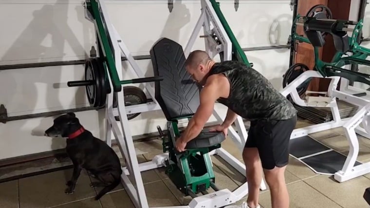 Muscular person in gym setting up chest press machine