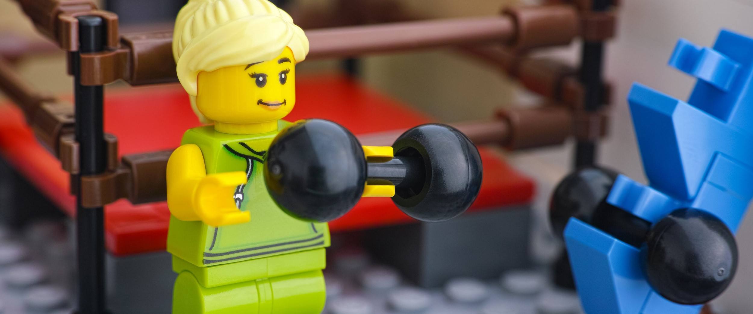 Lego woman minifigure lifting weights in a gym