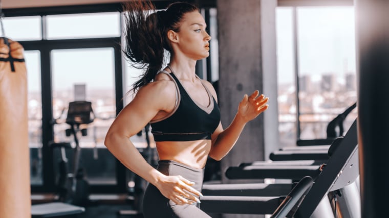Long-haired muscular person running on treadmill