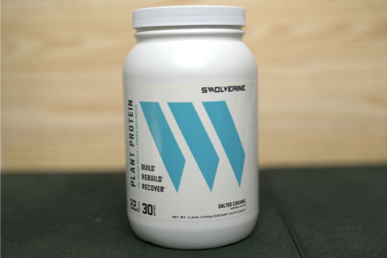 A container of Swolverine Plant Protein in front of a wood background