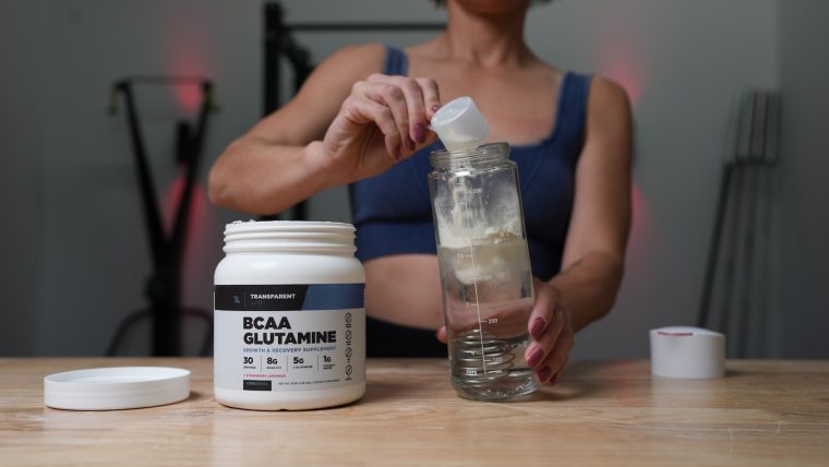 Breaking Muscle team member pours a scoop of Transparent Labs BCAA Glutamine into a bottle.