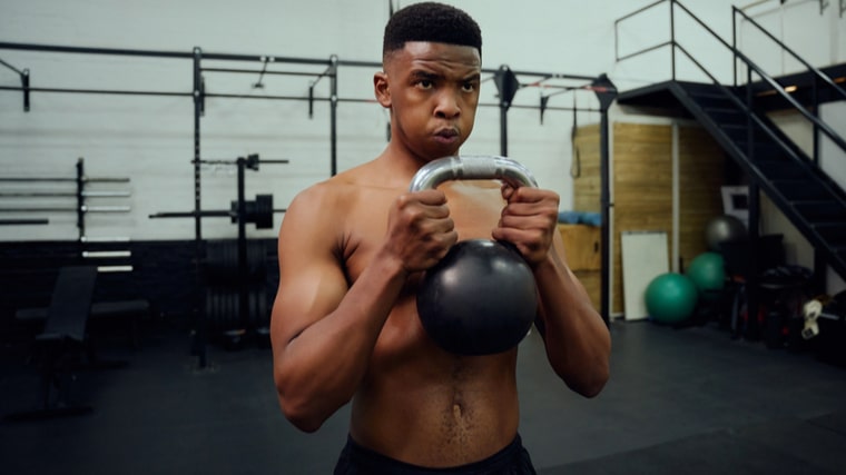 person in gym breathing hard while lifting kettlebell