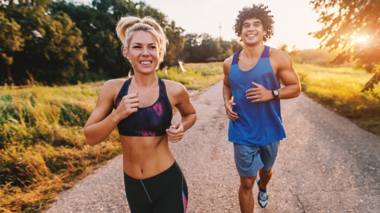 Two people running outdoors in sunlight