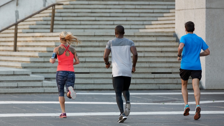 three people running outdoors towards stairs