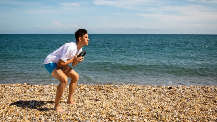 person near beach performing kettlebell exercise