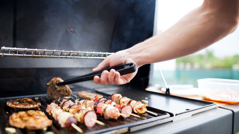 person grilling meat outdoors