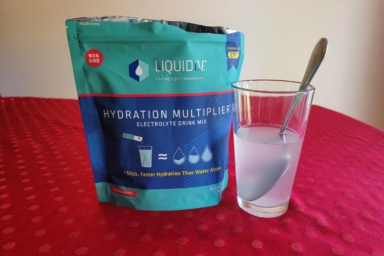 A pouch of Liquid IV and the powder mixed in a glass of water