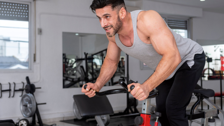 Muscular person in gym using spin bike