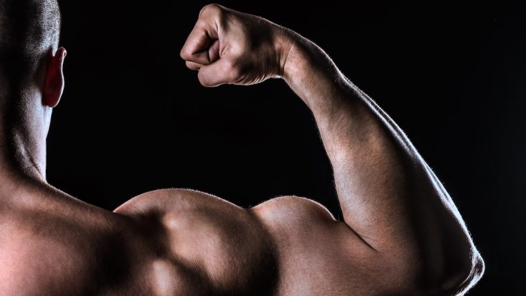 Close shot of a man flexing his biceps from behind.