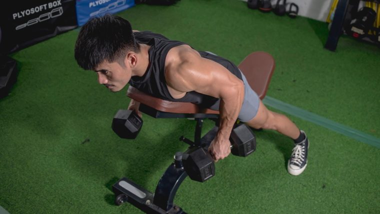 Man performing chest-supported row using dumbbells.