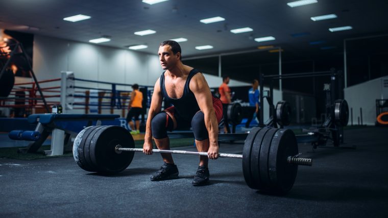 Male powerlifter prepares to perform a conventional barbell deadlift.
