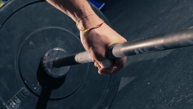 Close-up shot of a person's hand grabbing a barbell.